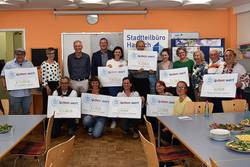 Eine Gruppe von Menschen hält Schilder mit Geldspenden für verschiedene Organisationen.